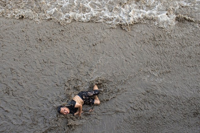 Homem tenta sair do rio Qiantang após cair de uma ponte, na província de Zheijand, na China - 26/07/2016