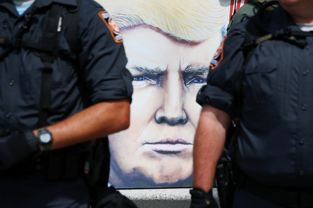 Pintura do rosto do candidato republicano à presidência dos Estados Unidos, Donald Trump, é vista entre policiais, próximo ao local onde ocorre a Convenção Nacional do Partido Republicano, em Cleveland - 21/07/2016