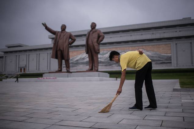 Funcionário faz serviço voluntário varrendo o chão em frente às estátuas que homenageiam os ditadores Kim Il-Sung e Kim Jong-Il, em Pyongyang, Coreia do Norte
