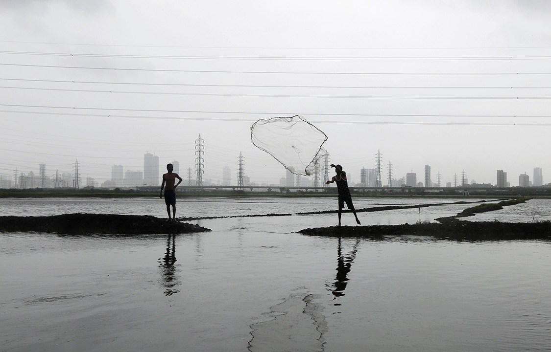 Pescador lança sua rede em um lago inundado na cidade de Mumbai, na Índia
