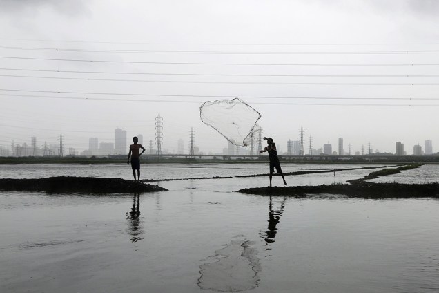 Pescador lança sua rede em um lago inundado na cidade de Mumbai, na Índia - 20/07/2016