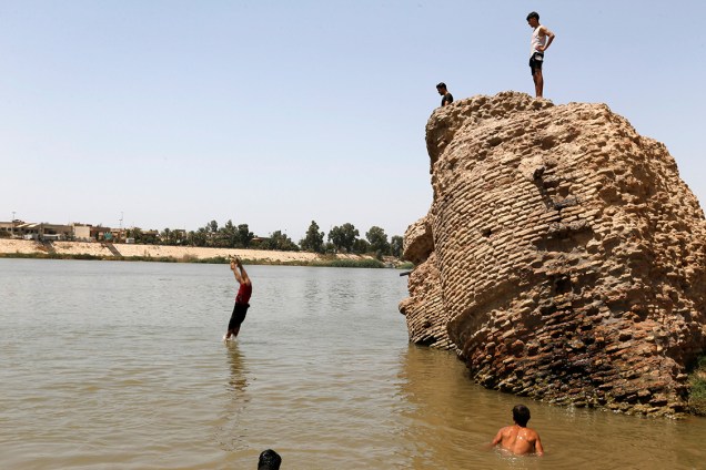 Garotos mergulham no Rio Tigre para se refrescar em um dia quente de verão, na região norte de Bagdá, distrito de Adhamiya, no Iraque - 20/07/2016
