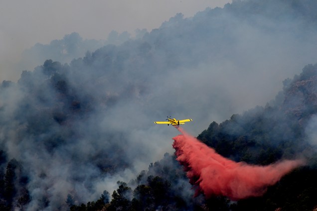 Avião sobrevoa floresta na cidade de Artana, na Espanha, com substância que retardada o fogo que tem atingido a região - 26/07/2016