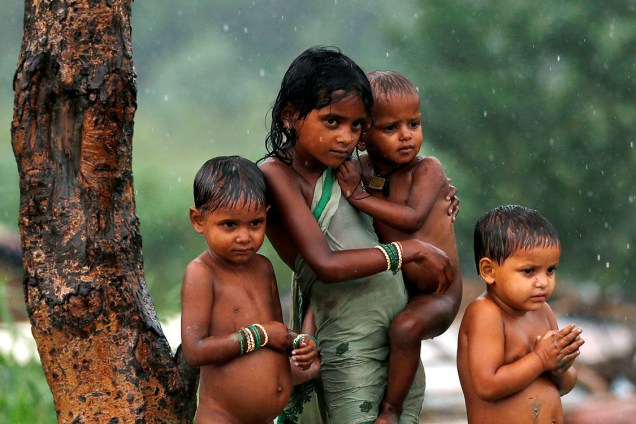 Crianças se protegem da chuva debaixo de uma árvore em Nova Délhi, na Índia - 26/07/2016