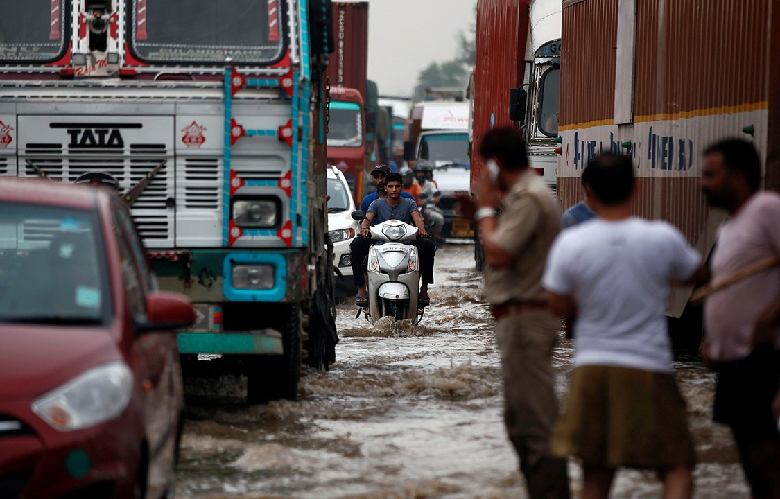 Veículos tentam passar por regiões alagadas após fortes tempestades atingirem a região de Gurugram, nos arredores de Nova Délhi, Índia