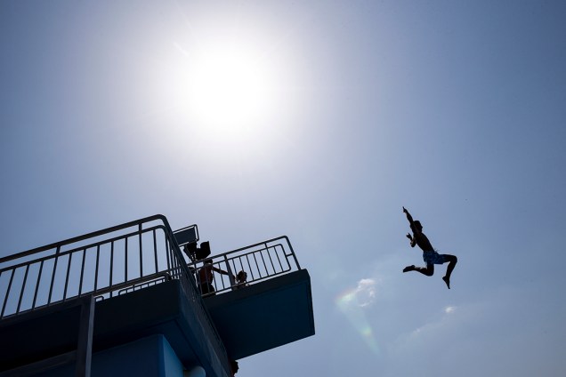 Garoto salta de uma plataforma para se refrescar em uma piscina na vila de Zllakuqan, próximo a Klina, no Kosovo, onde as temperaturas atingiram 35°C - 25/07/2016