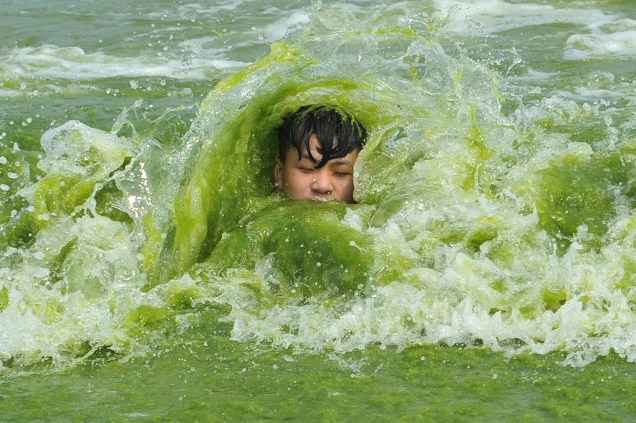 A boy plays on a algae-covered beach in Qingdao, Shandong province, China, July 18, 2016. Picture taken July 18, 2016. REUTERS/Stringer ATTENTION EDITORS - THIS PICTURE WAS PROVIDED BY A THIRD PARTY. EDITORIAL USE ONLY. CHINA OUT. NO COMMERCIAL OR EDITORIAL SALES IN CHINA.