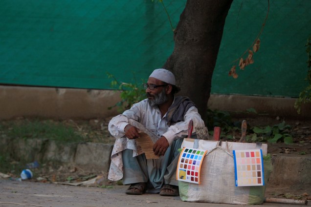Trabalhador senta em uma calçada ao lado de sua caixa de ferramentas em Islamabad, no Paquistão - 29/07/2016