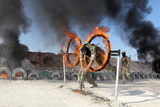 Soldado do Exército de Libertação da Síria salta por um arco em chamas durante treinamento na província de Hama, Síria - 29/07/2016