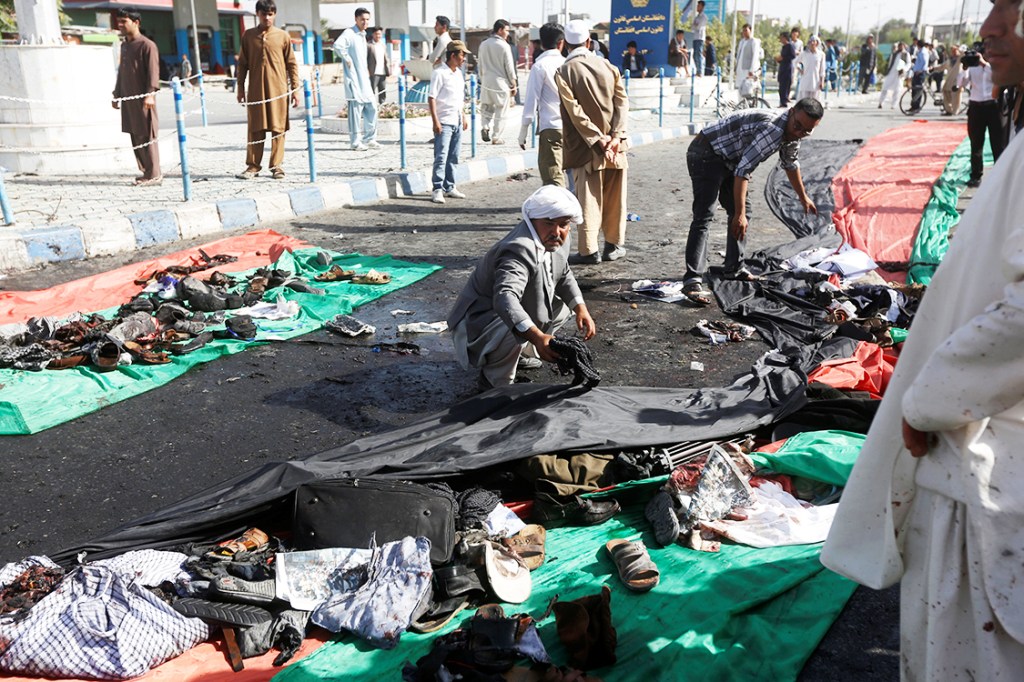 Afegão recolhe roupas das vítimas do atentado com homens-bomba, na cidade de Cabul, no Afeganistão. Pelo menos 61 pessoas morreram - 23/07/2016