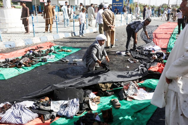 Afegão recolhe roupas de vítimas do atentado com homens-bomba, na cidade de Cabul, no Afeganistão. Pelo menos 61 pessoas morreram - 23/07/2016