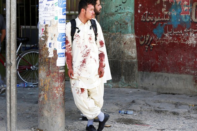 Afegão com marcas de sangue na roupa, próximo ao local onde homens-bomba se explodiram na capital do Afaganistão, Cabul - 23/07/2016