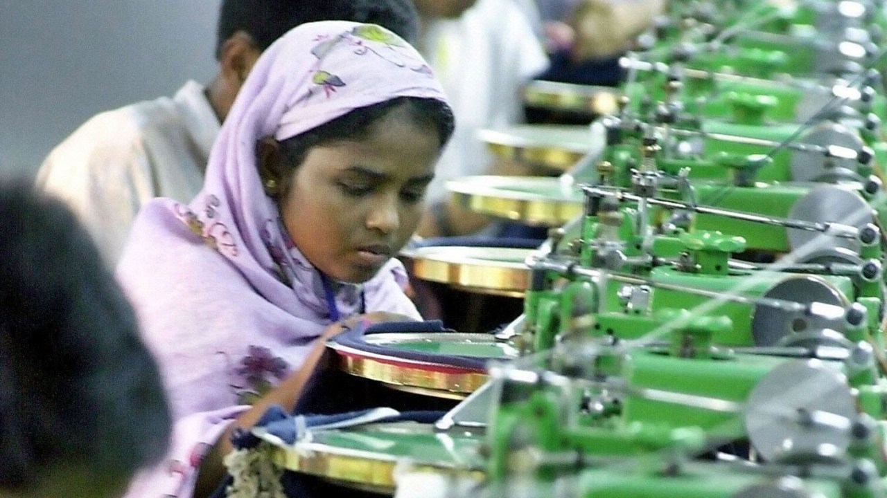 Menina trabalha em fábrica têxtil em Ashulia, nos arredores de Dhaka, em Bangladesh - 11/12/2004