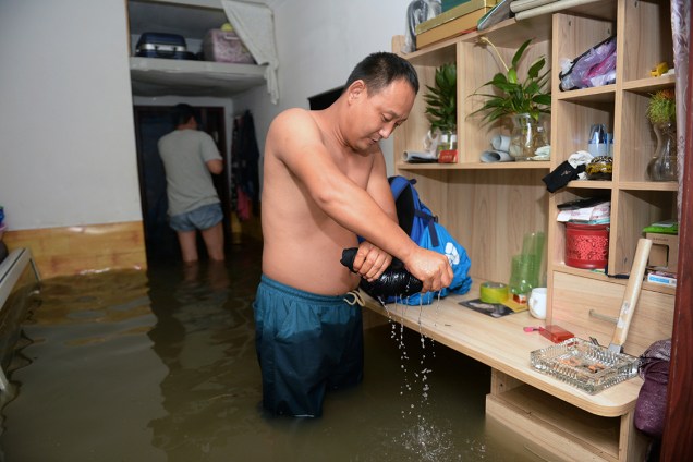 Homem tira água de suas roupas, após fortes chuvas provocarem inundações, no Distrito de Changping, em Pequim, na China - 21/07/2016