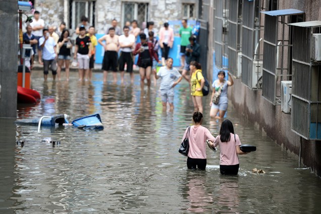 Pessoas caminham em área inundada, após fortes chuvas atingirem o Distrito de Changping, em Pequim, na China - 21/07/2016