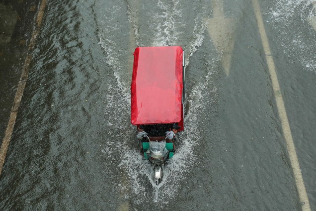 Triciclo anda em rua inundada, de Pequim, na China, após fortes chuvas atingirem a região - 20/07/2016
