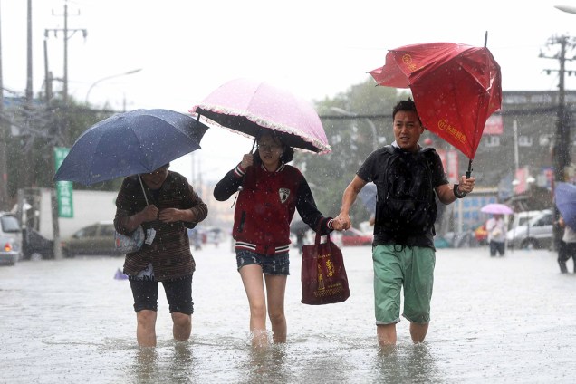 Pessoas caminham em rua inundada de Pequim, na China, após fortes chuvas atingirem a região - 20/07/2016