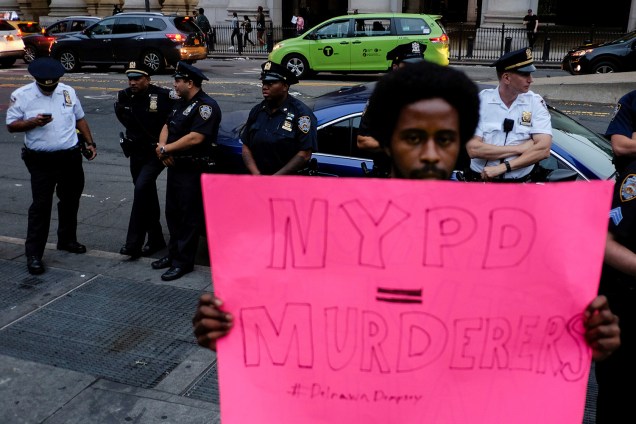 Homem segura um cartaz escrito "Policia de Nova York assassinos"