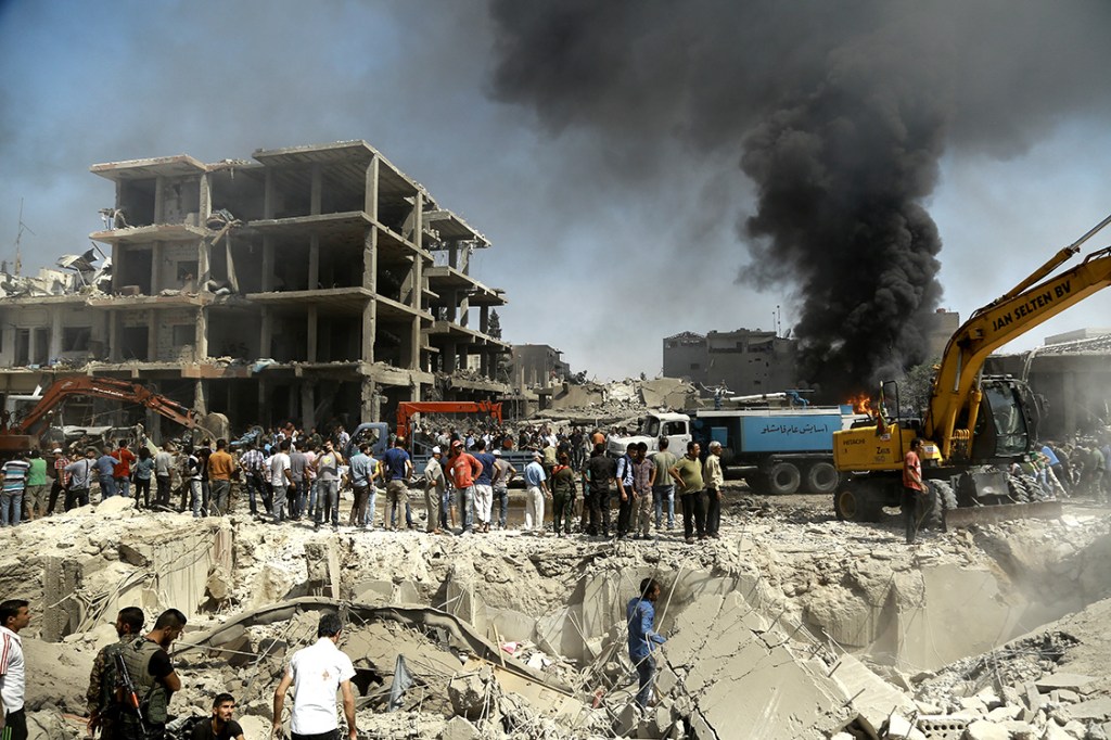 Moradores observam local onde um atentado com bomba, atribuído ao Estado Islâmico, matou 44 pessoas na cidade de Qamishli, na Síria