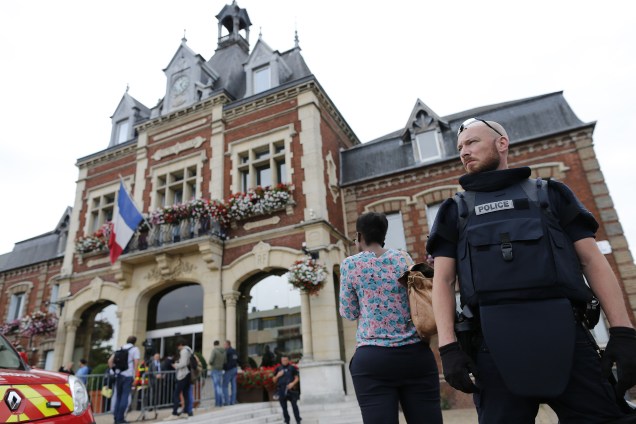 Agente da polícia fica de guarda em frente à prefeitura de Saint-Etienne-du-Rouvray, norte da França, na sequência de uma tomada de reféns em uma igreja que terminou com a morte de um padre - 26/07/2016