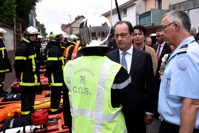 O presidente francês, François Hollande cumprimenta um bombeiro em sua chegada à cidade de Saint-Etienne-du-Rouvray na sequência de um ataque que matou um padre dentro de uma igreja da cidade - 26/07/2016