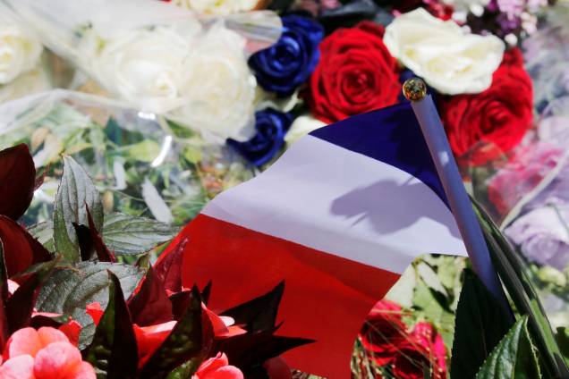 Flores são colocadas junto com uma bandeira da França em um memorial improvisado no local do ataque com um caminhão em Nice - 15/07/2016