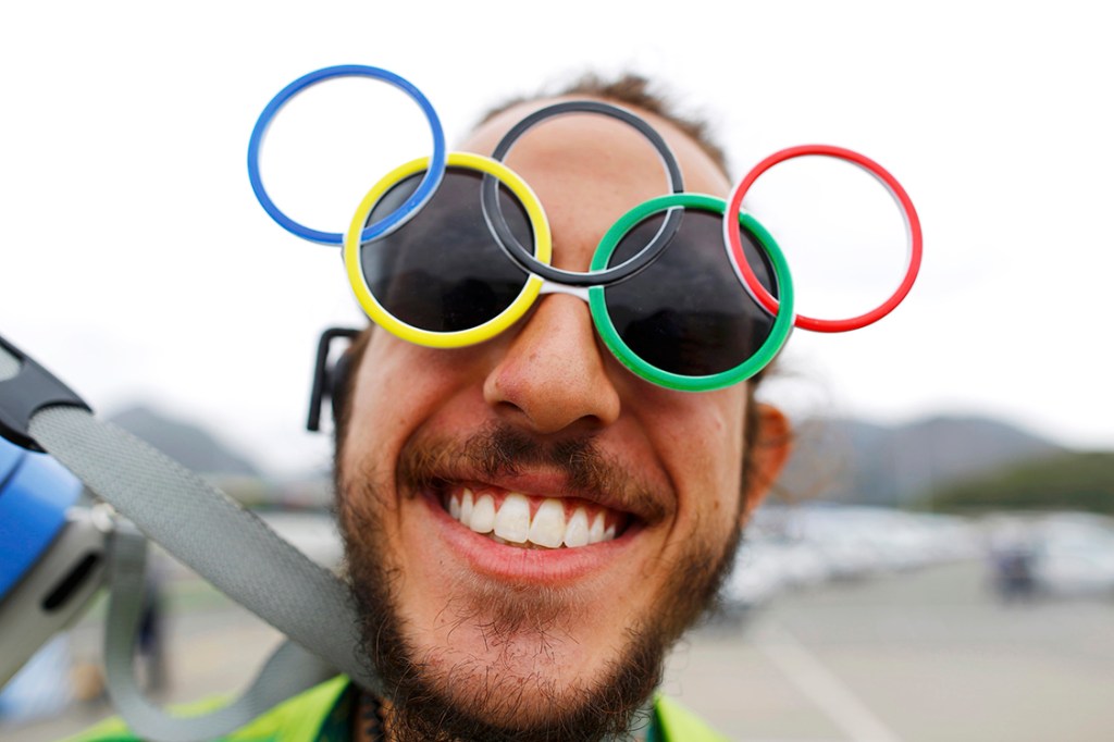 Voluntário usa óculos com símbolo das Olímpiadas, os aros interligados, na Vila Olímpica, Rio de Janeiro