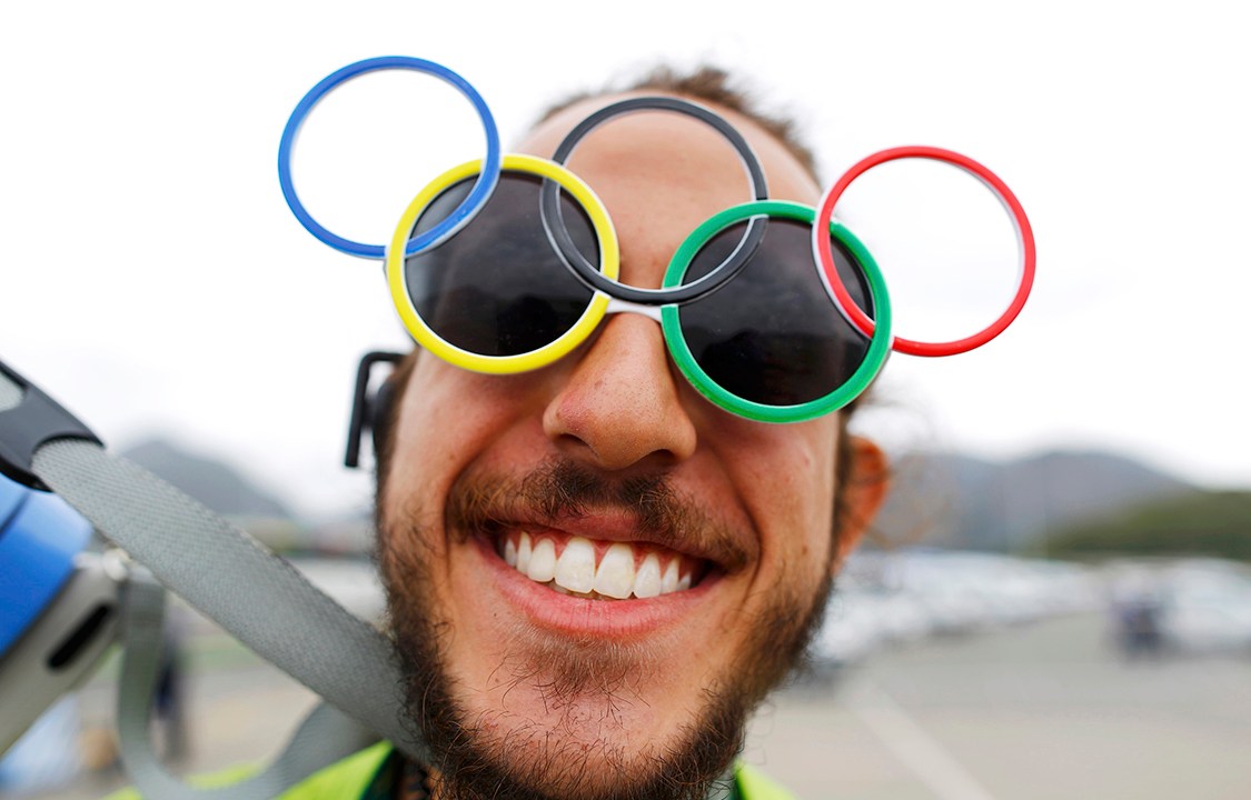 Voluntário usa óculos com símbolo das Olímpiadas, os aros interligados, na Vila Olímpica, Rio de Janeiro