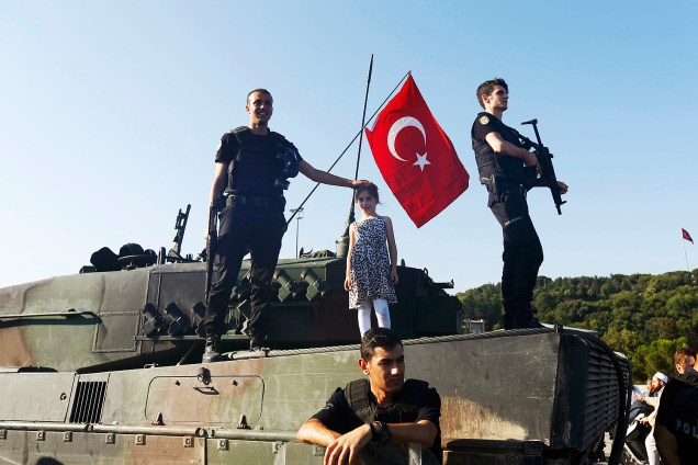 Uma criança é fotografada ao lado de policiais turcos em tanque usado em tentativa de golpe