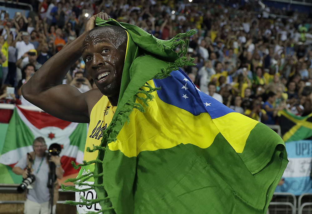 Usain Bolt from Jamaica celebrates winning the gold medal in the men's 200-meter final, with the Brazilian flag, during the athletics competitions of the 2016 Summer Olympics at the Olympic stadium in Rio de Janeiro, Brazil, Thursday, Aug. 18, 2016. (AP Photo/Matt Slocum)
