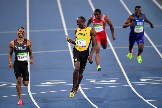Velocista jamaicano Usain Bolt sorri para o canadense Andre De Grasse enquanto cruza a linha de chegada da prova semi-final de 200m rasos