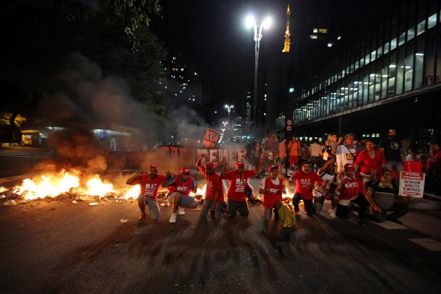 Manifestantes se ajoelham em frente à polícia, durante protesto contra o impeachment na Avenida Paulista
