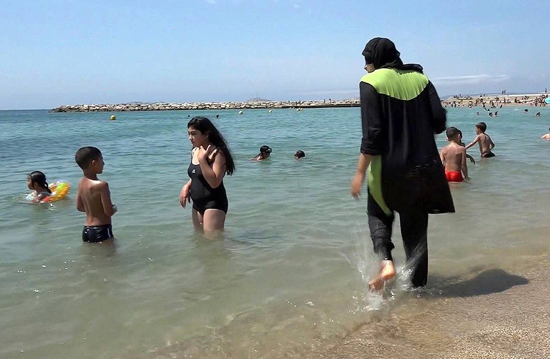 Mulher é fotografada na praia vestindo um "burquini", espécie de roupa de banho que cobre todo o corpo para que mulheres da religião muçulmana pudessem frequentar a praia