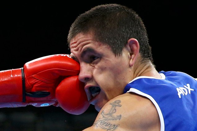 O boxeador argentino Ignacio Perrin recebe um golpe durante luta contra o tailandês Amnat Ruenroeng na disputa do peso ligeiro