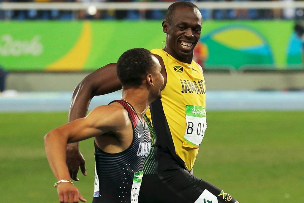 O jamaicano Usain Bolt brinca com o canadense Andre De Grasse na chegada da prova eliminatória dos 200m rasos