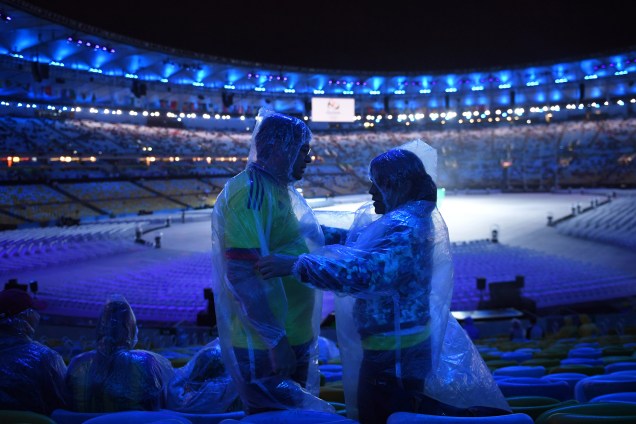 Público se protege com capas de chuva antes da cerimônia de encerramento da Rio-2016, no Maracanã