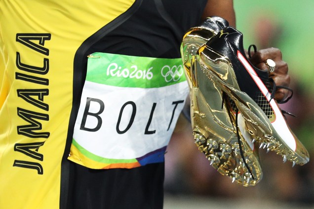 Usain Bolt segura suas sapatilhas douradas após conquistar o tri olímpico nos 100m rasos