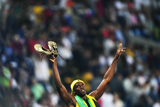 Usain Bolt comemora com as sapatilhas douradas a conquista do tri olímpico nos 100m rasos