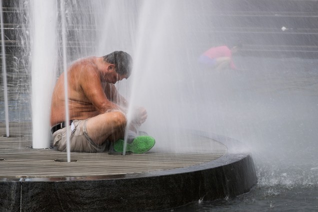 Sob um calor de quase 40 graus, homem se refresca em uma fonte no Parque Washington na cidade de Nova York