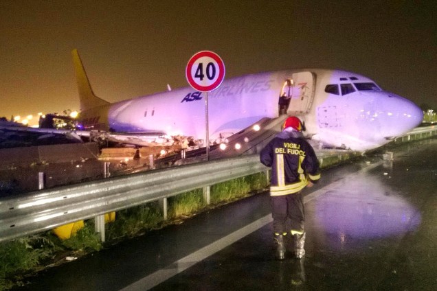 Bombeiro fotografado em frente a um avião de carga que saiu da pista após o pouso e deslizou para uma estrada local em Orio al Serio, perto de Milão, na Itália - 05/08/2016