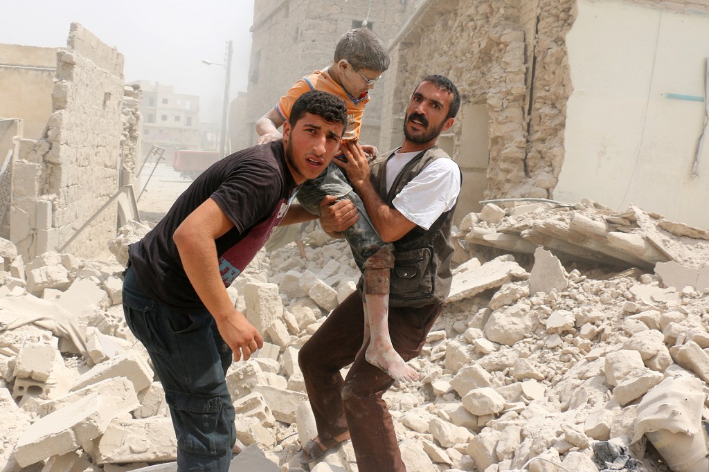 Homens sírios resgatam um garoto em meio dos escombros