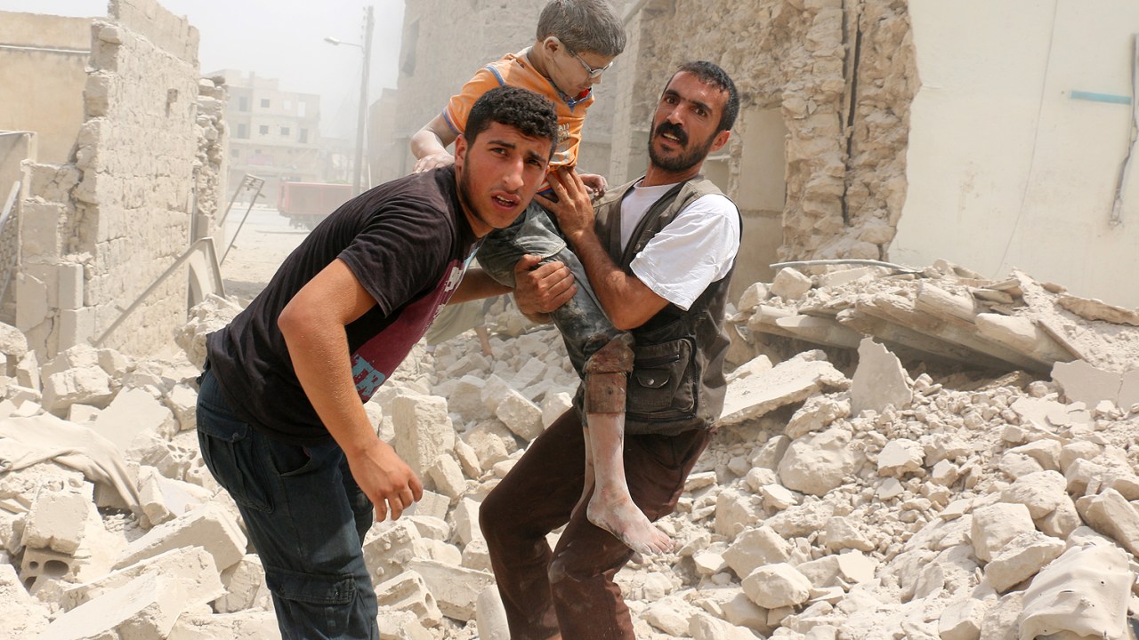 Homens sírios resgatam um garoto em meio dos escombros