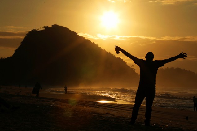 Homem acompanha amanhecer do Sol na Praia de Copacabana, no Rio de Janeiro (RJ) - 23/08/2016