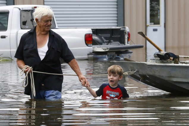 Senhor e seu neto caminham por uma área alagada em St. Amant, em Louisiana, após fortes tempestades atingirem a região, nos Estados Unidos - 15/08/2016