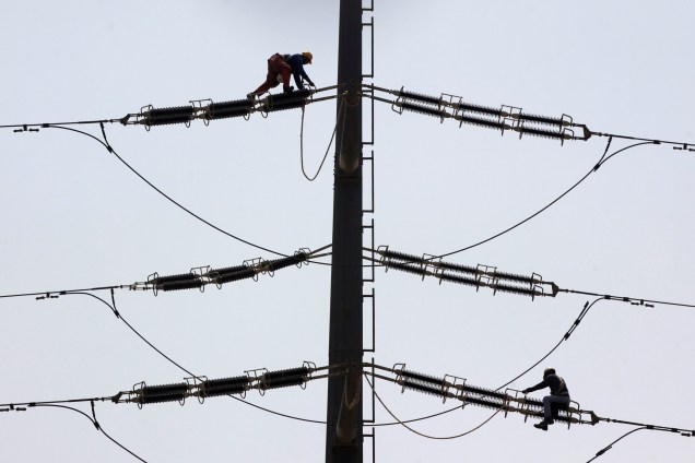 Trabalhadores consertam uma torre de transmissão de energia em Karachi, no Paquistão - 22/08/2016