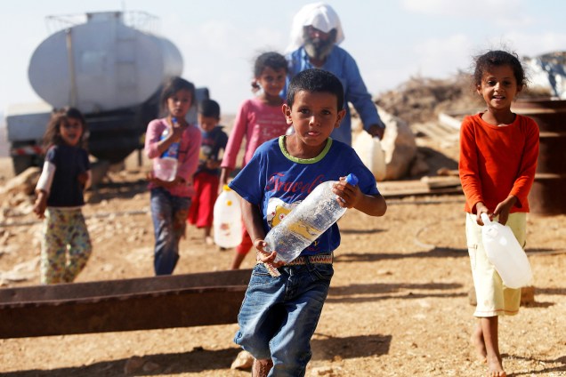Crianças palestinas carregam garrafas d'água, próximos à vila de Yatta - 23/08/2016