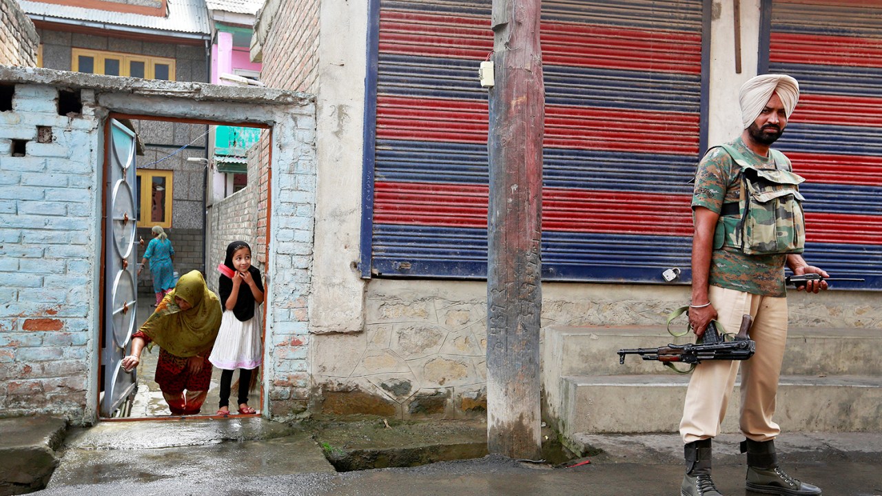 Garota observa soldado em uma rua de Srinagar, na Caxemira, A cidade permanece sob toque de recolher após semanas de intensos conflitos na região - 19/08/2016