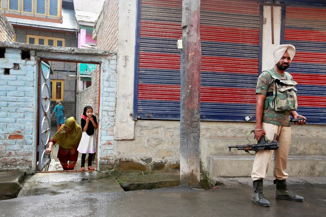 Garota observa soldado em uma rua de Srinagar, na Caxemira, A cidade permanece sob toque de recolher após semanas de intensos conflitos na região - 19/08/2016