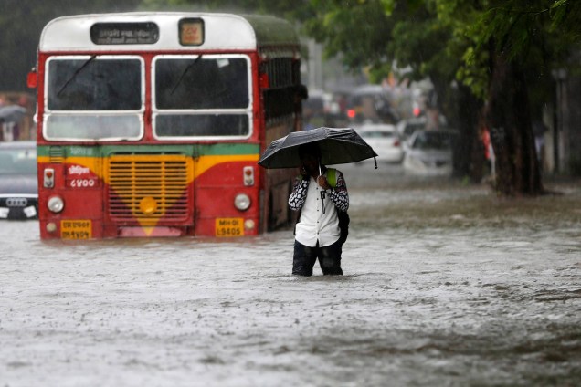 Homem passa por um ônibus encalhado em uma estrada inundada pelas fortes chuvas em Mumbai, na Índia - 05/08/2016