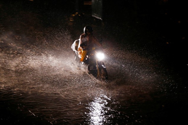 Motociclista passa por área alagada depois de fortes tempestades atingirem a região de Nova Délhi, na Índia - 01/08/2016